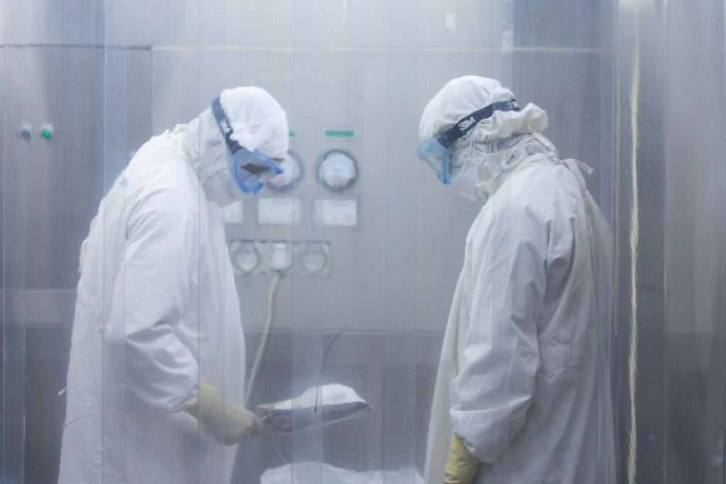 Two scientists in protective suits working in a cleanroom.